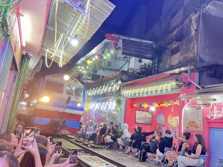 Train rushing past Hanoi Train Street cafés at night