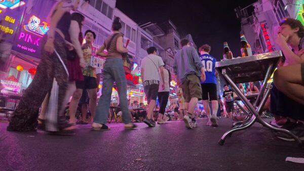Low-angle street shot with crowds and neon signs